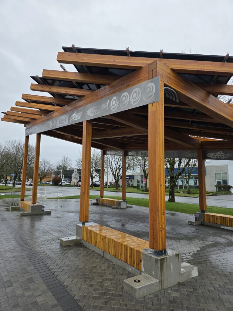 Wood pergola structure at George Ingham Plaza with engraved beam detail and open slatted roof design